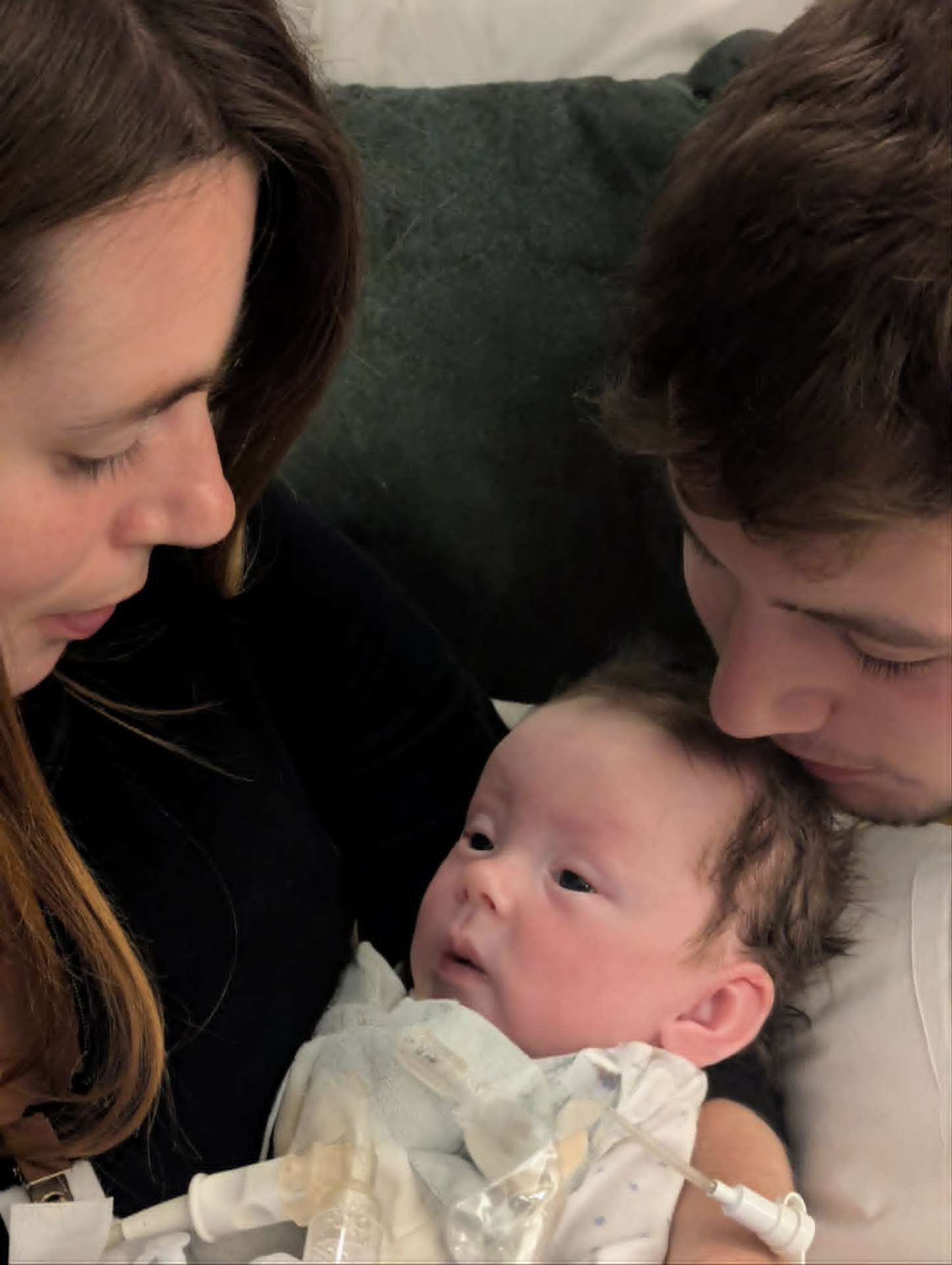 Parents kissing baby Noah, his eyes open