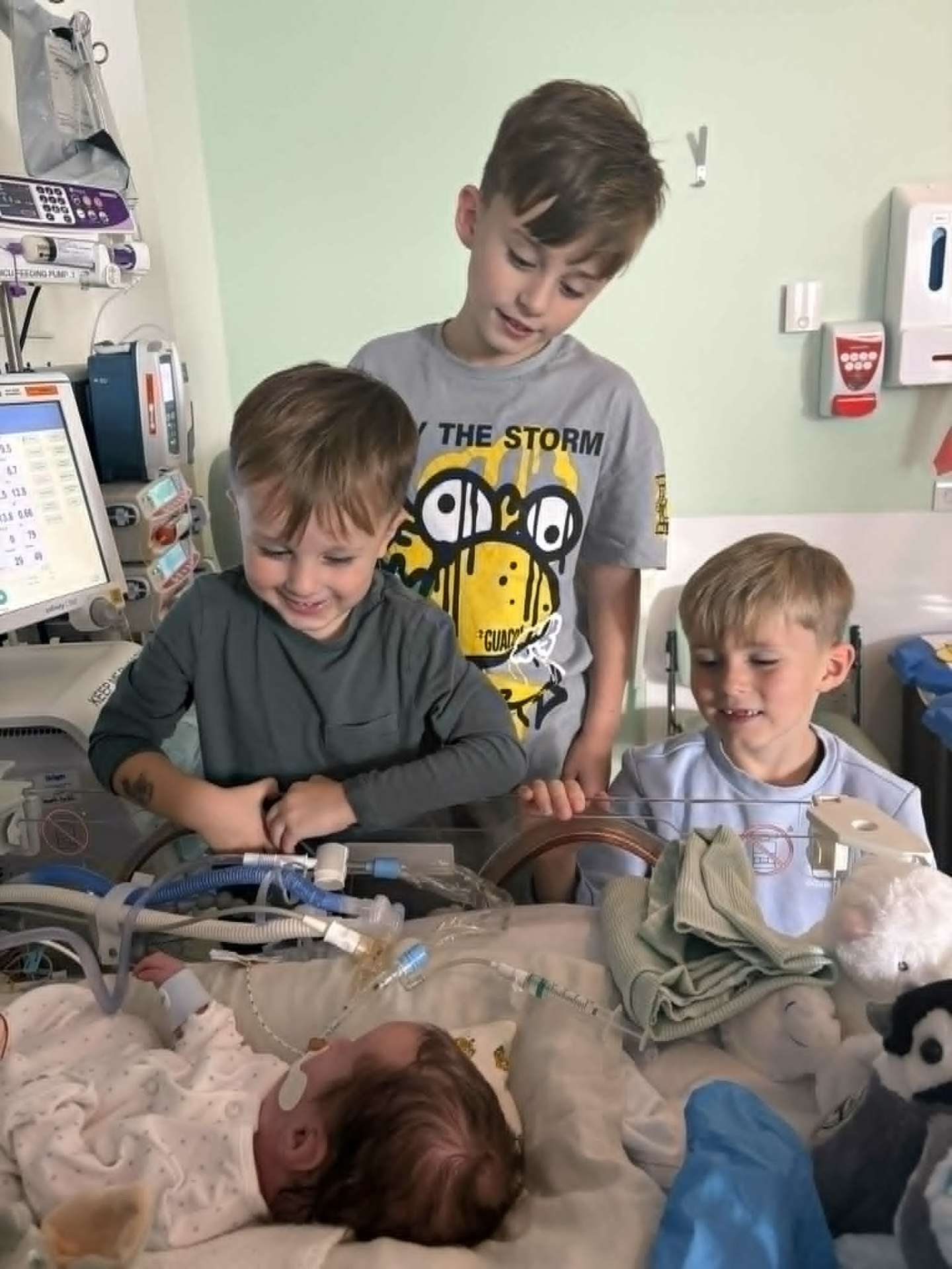 Noah's brothers smiling by the incubator